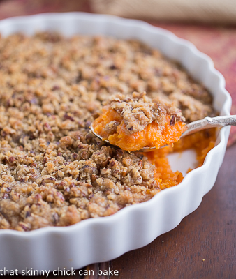 Praline Topped Sweet Potato Casserole in a white bowl with a spoon.