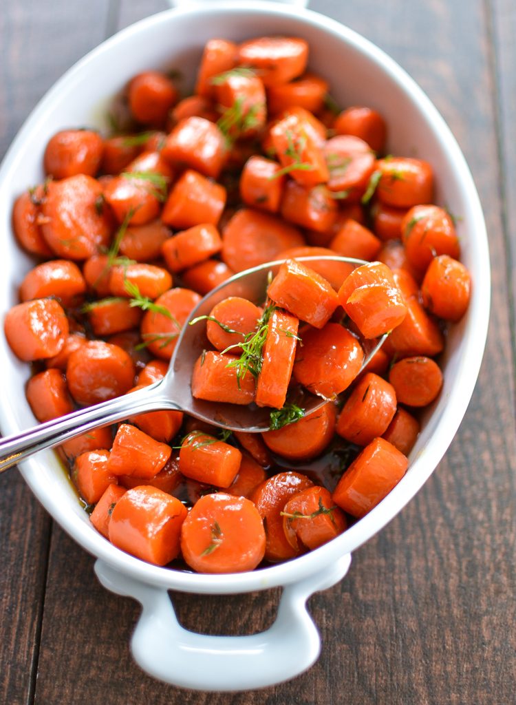 Bourbon Maple Glazed Carrots in a white bowl with a spoon.