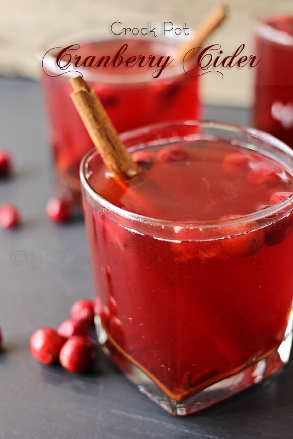 Crockpot Cranberry Cider in two glasses with cinnamon sticks and cranberries.