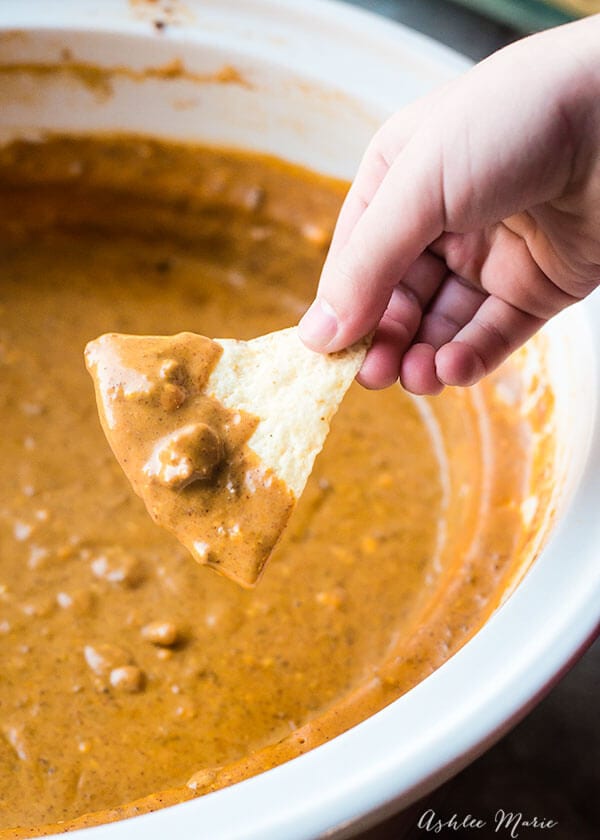 Chili's Copycat Spicy Queso Dip with someone holding a tortilla chip.