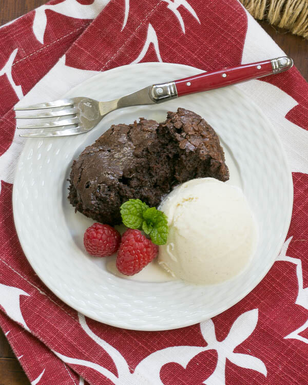 Slow Cooker Brownie Dessert on a white plate with ice cream and fresh berries.