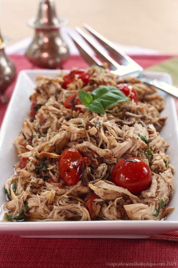 Slow Cooker Tomato Basil Pulled Chicken on a plate with a fork.