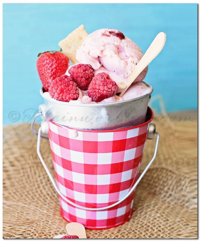 Double Berry Cheesecake Frozen Yogurt in a metal pail with a spoon.