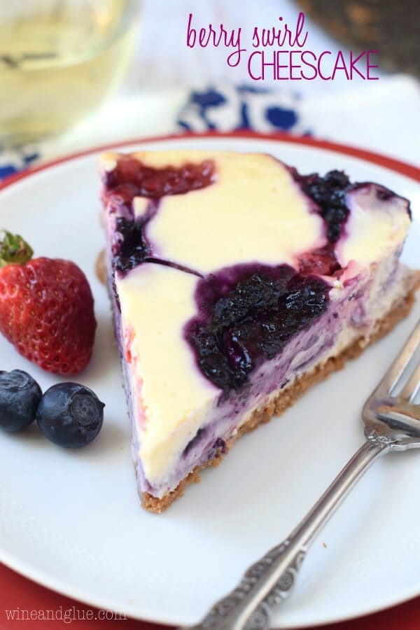 Berry Swirl Cheesecake on a white plate with fresh berries and a fork for a memorial day dessert.