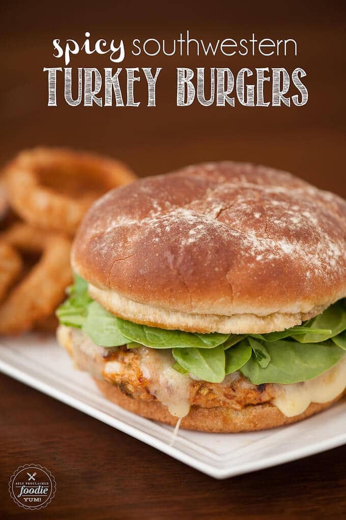 Spicy Southwestern Turkey Burgers on a white plate with onion rings on a memorial day holiday.