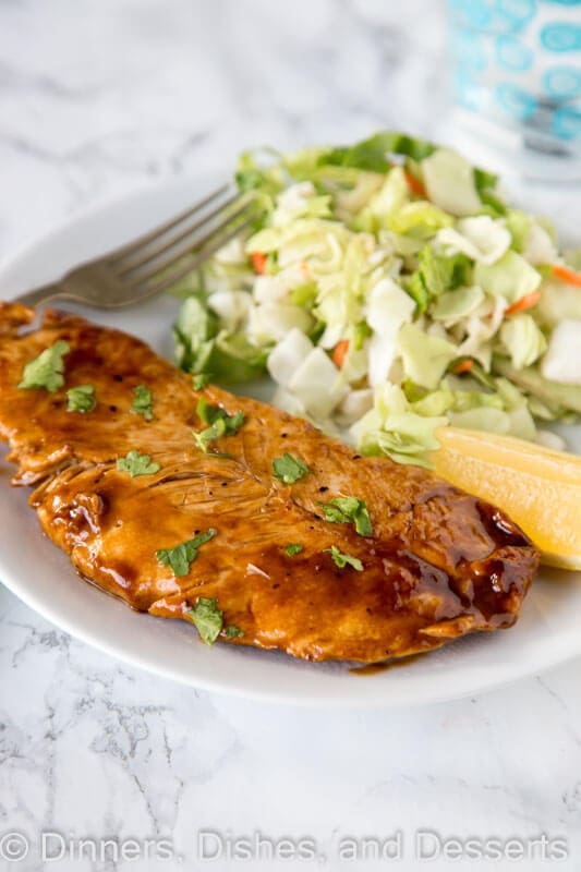 A plate of lemon turkey cutlet on a plate with lemon wedge