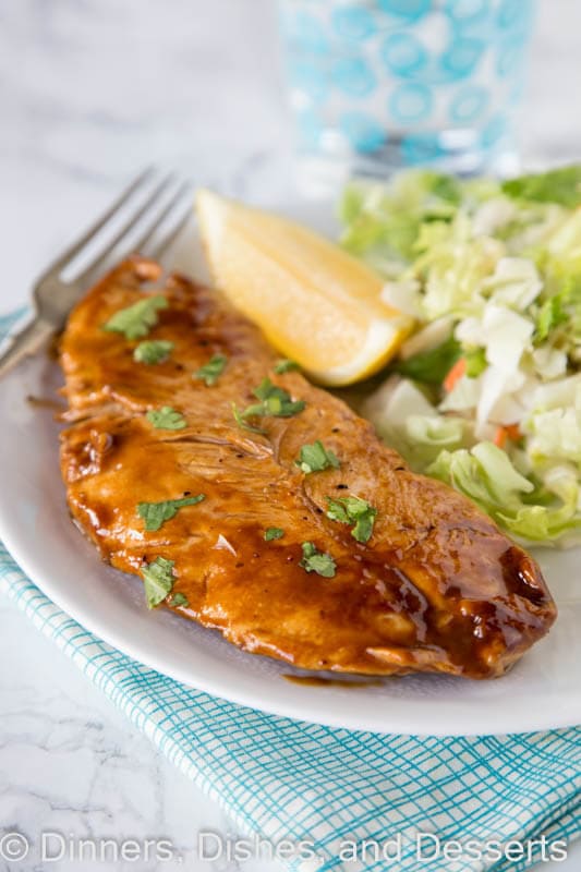 A plate of lemon turkey cutlet on a plate with lemon wedge