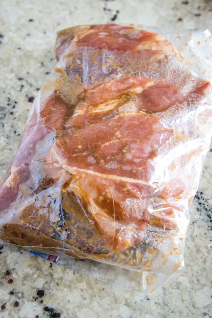 A plastic bag filled with marinating pieces of pork