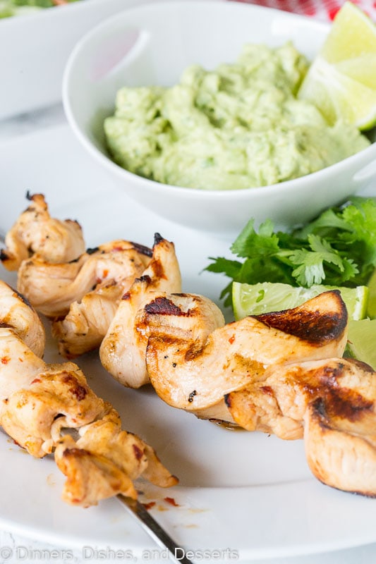 grilled chicken on skewers with avocado dipping sauce on a plate