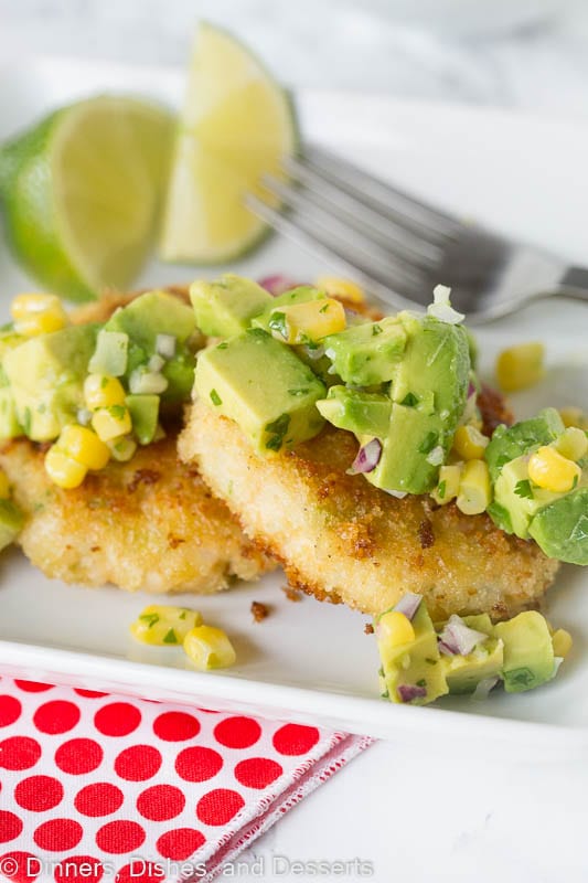 Shrimp cakes topped with avocado corn salsa on a plate with  fork