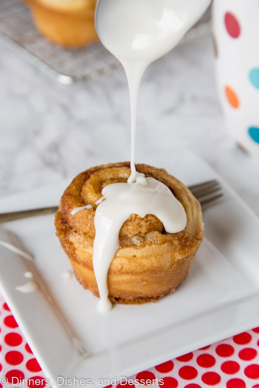 cinnamon roll muffin with vanilla glaze being drizzled on top