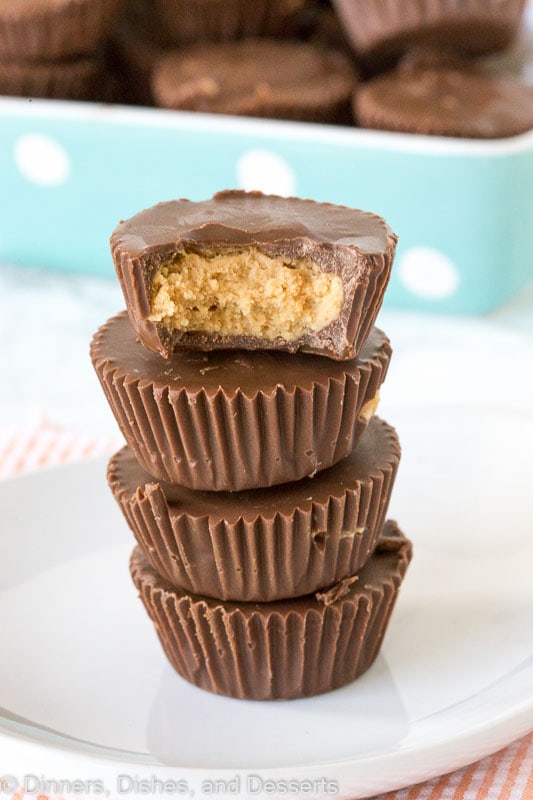 homemade peanut butter cups stacked, one has a bite taken out of it.