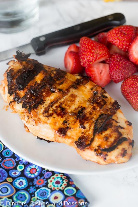 a piece of grilled chicken on a plate next to strawberries