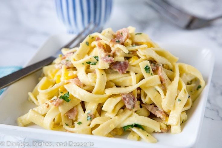 A close up of pasta carbonara with corn and chilies on a plate