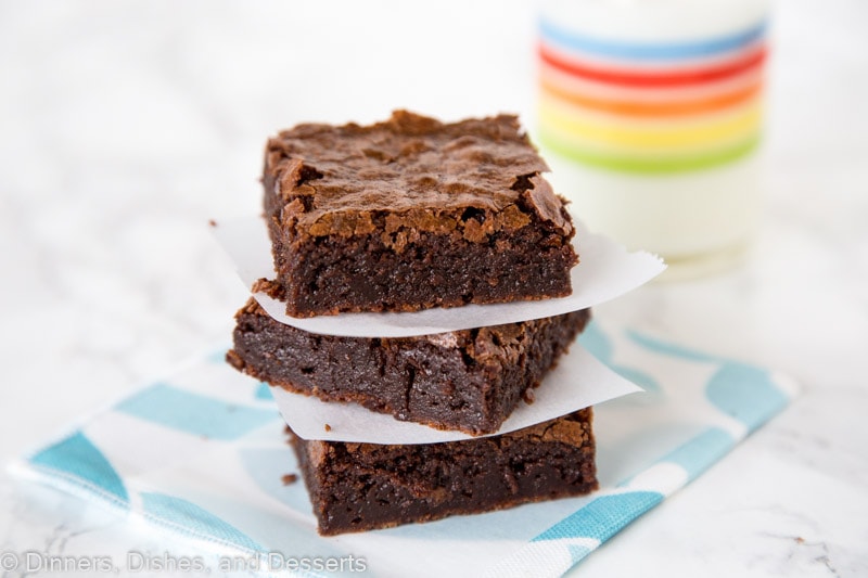 brownies stacked next to a glass of milk