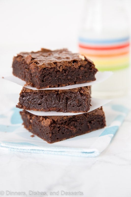 brownies stacked next to a glass of milk