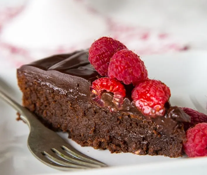 Flourless Nutella Cake - A rich and fudgy flourless chocolate cake full of Nutella! Top with raspberries for hazelnuts for a decadent dessert.
