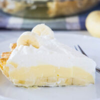 Close up of a slice of banana cream pie on a plate with a fork