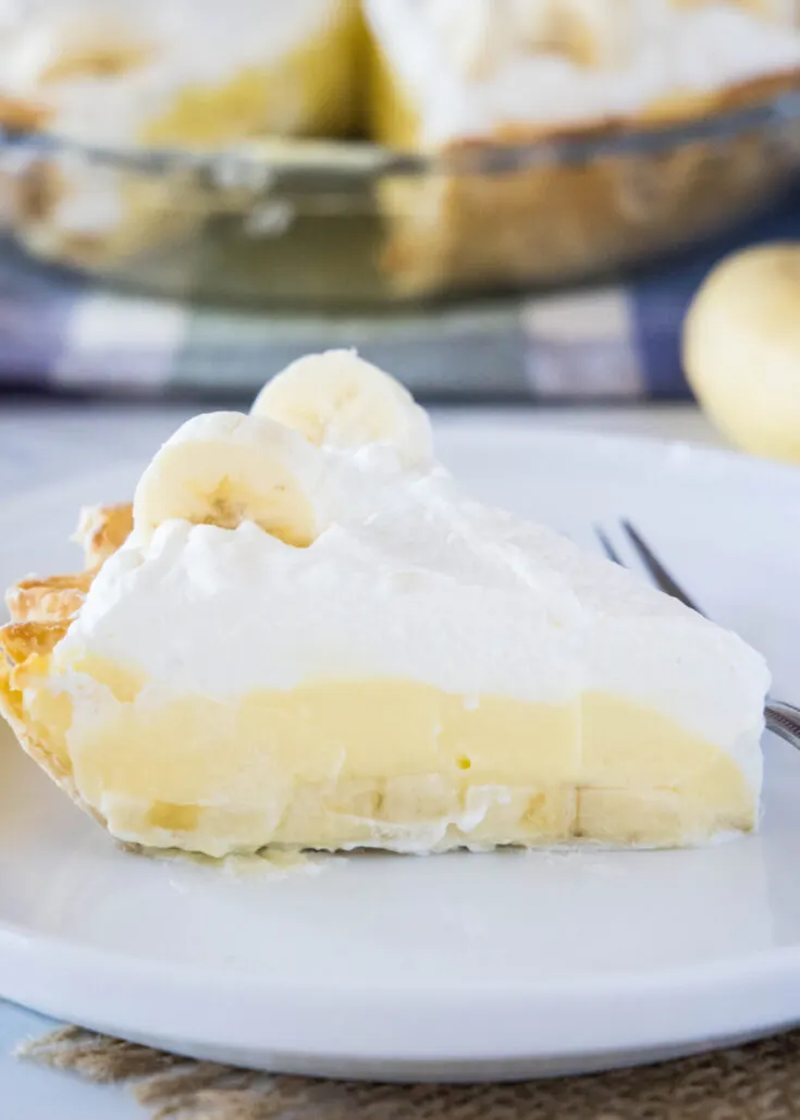 Close up of a slice of banana cream pie on a plate with a fork