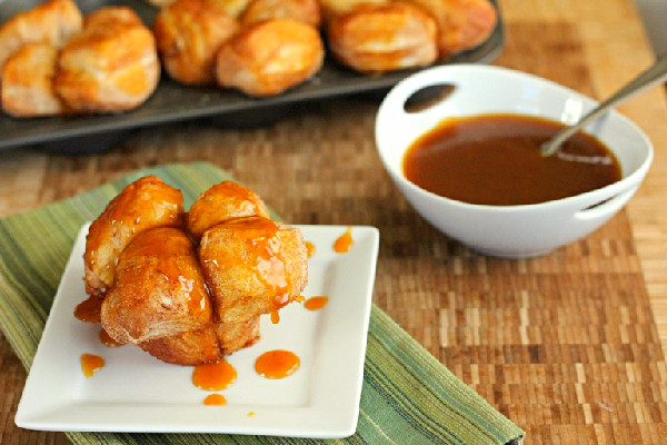 Pumpkin Caramel Monkey Bread Muffins on white plate with bowl of caramel