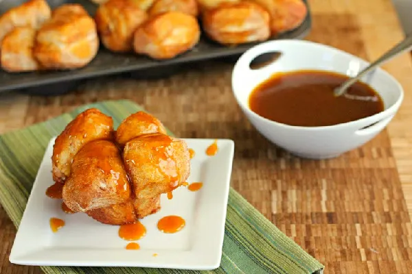 Pumpkin Caramel Monkey Bread Muffins on white plate with bowl of caramel