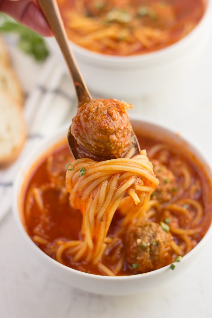 spaghetti and meatball soup in a bowl with a spoonful of food