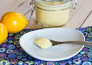 lemon curd on spoon on white plate with lemons on background