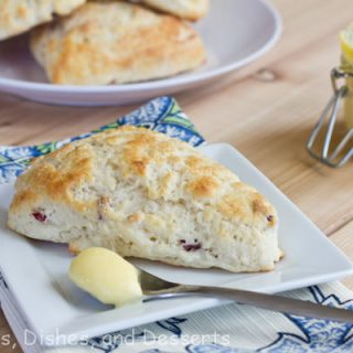 scone on white plate with lemon curd on spoon