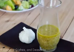 Roasted Garlic Vinaigrette in glass jar with head of garlic on black napkin