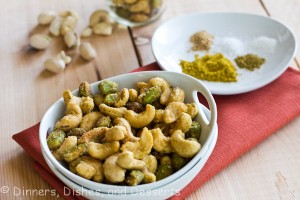 Indian Spiced Nuts in white bowl with plate of spices in background