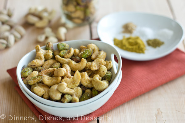 Indian Spiced Nuts in white bowl with plate of spices in background
