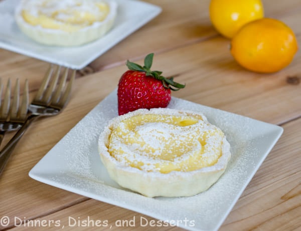 mini lemon tart on a white plate with lemons in the background