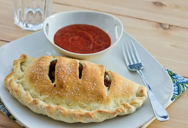 calzone on a plate with red sauce
