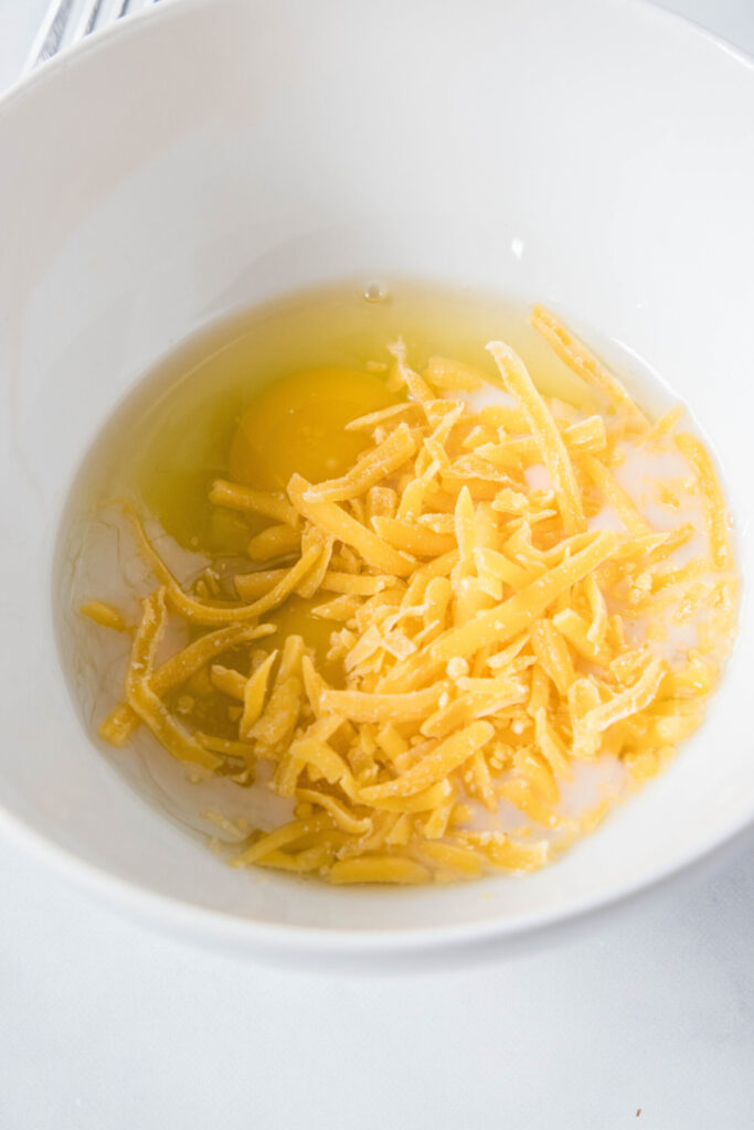 A bowl with eggs and shredded cheese