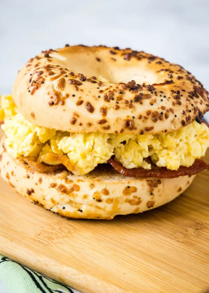 Close up of a bacon and egg bagel sandwich on a cutting board