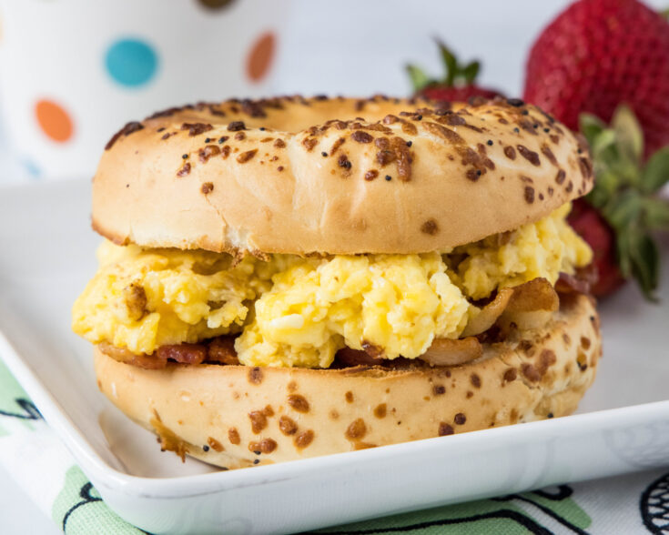 An egg and bacon bagel sandwich on a plate