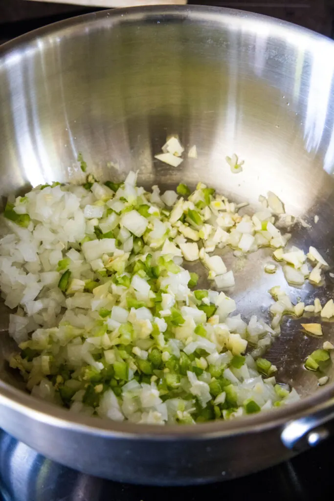 Onions, garlic, and jalapeños sautéing in a pot.