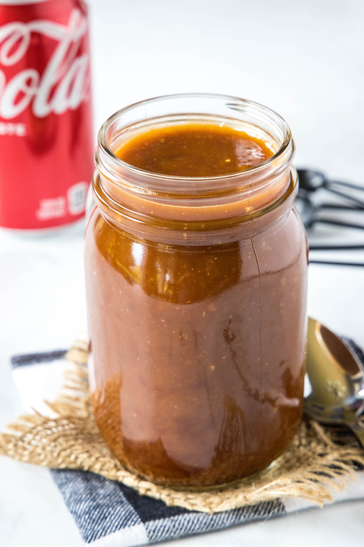 A jar of BBQ sauce with a can of Coke