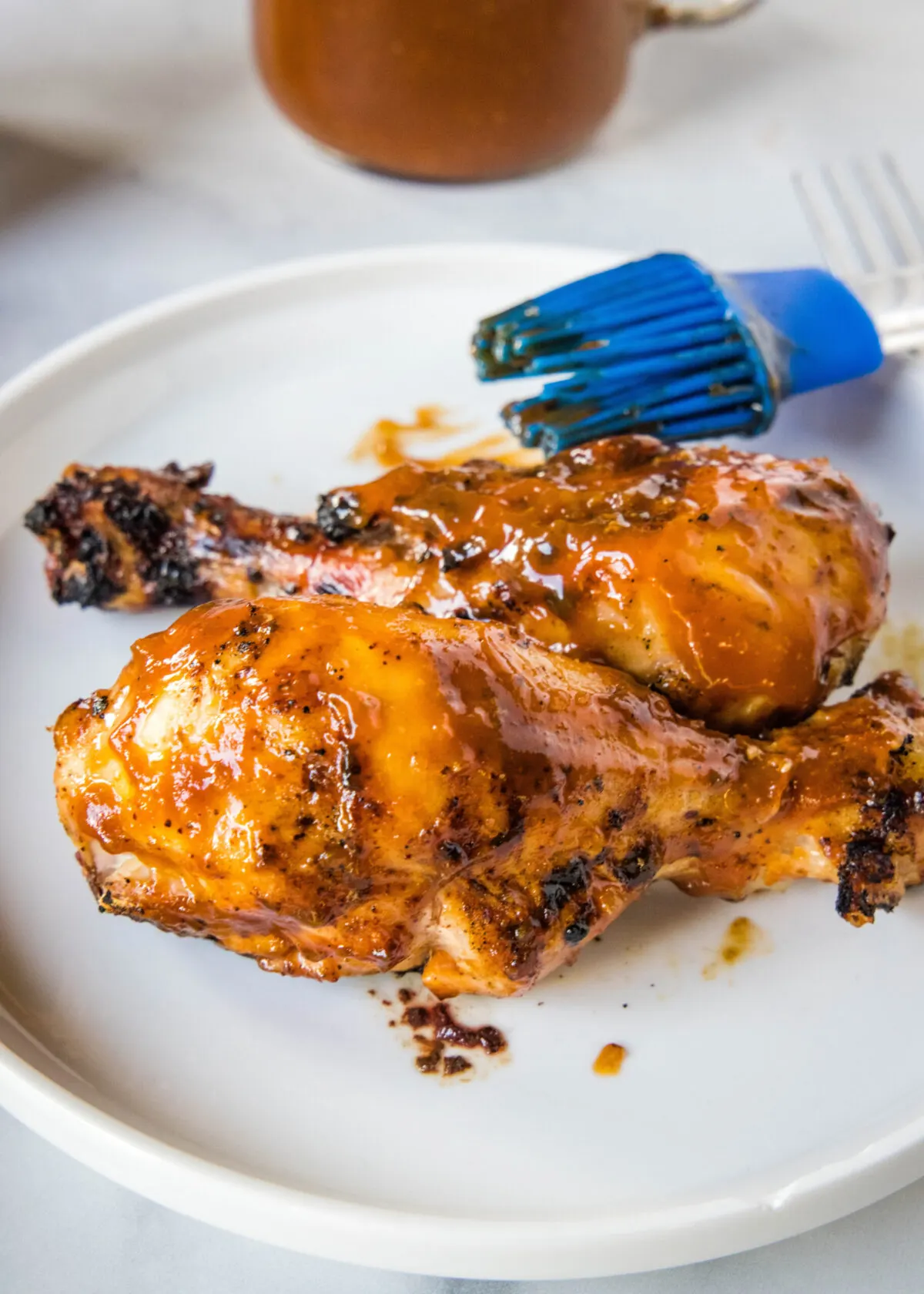A plate of barbecued chicken with a brush