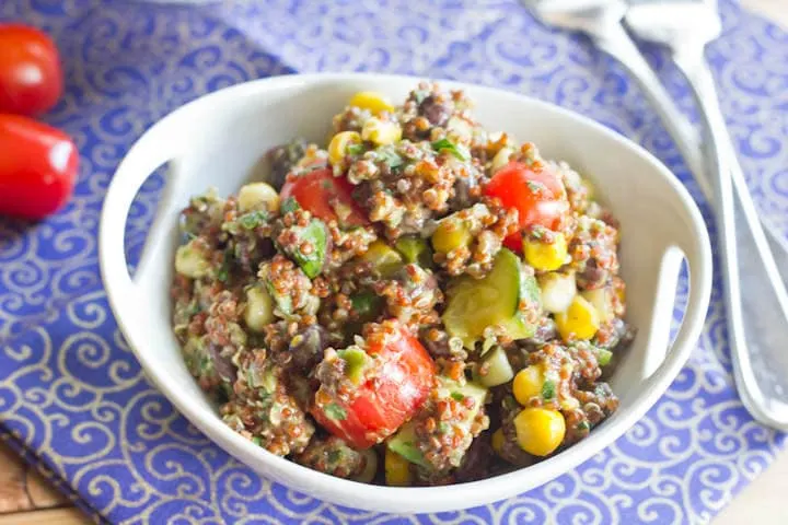 Quinoa Salad with corn, black beans, grape tomatoes, and zucchini, then topped with a creamy avocado dressing. Great warm or cold, so it is perfect for a picnic or barbeque