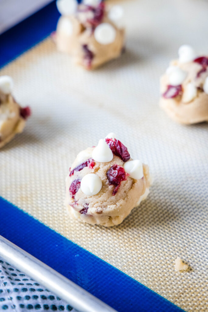 Balls of uncooked cranberry and white chocolate cookie dough on a silpat