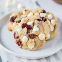 Close up of a plate with three white chocolate cranberry cookies on it