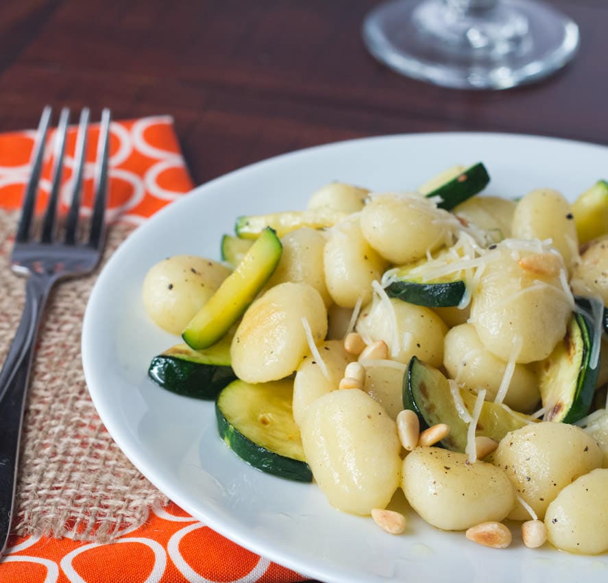 brown butter gnocchi with veggies and pinenuts on a plate