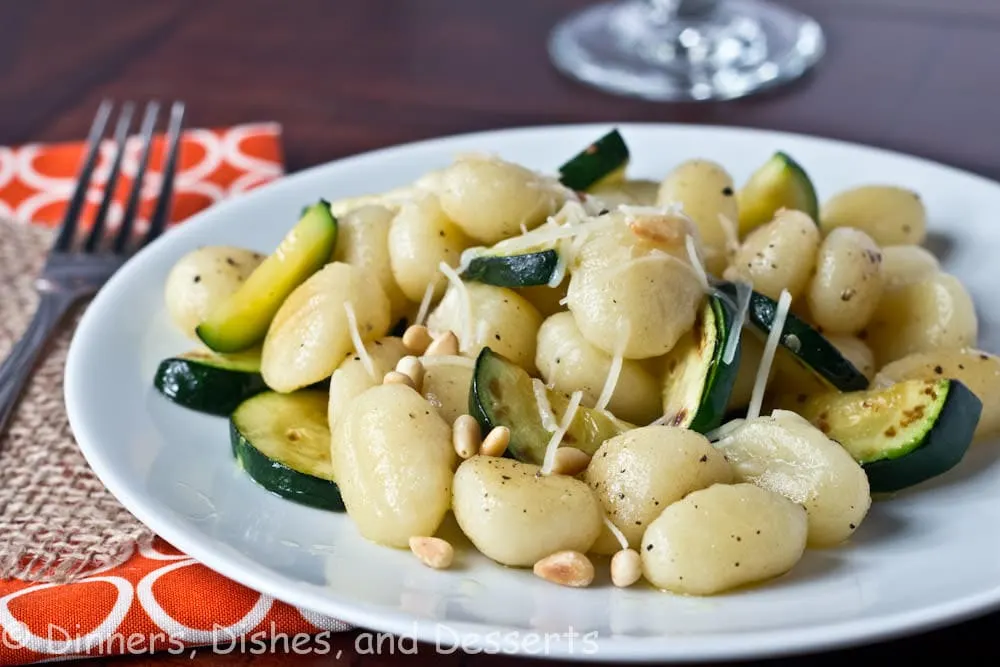 brown butter gnocchi with veggies and pinenuts on a plate