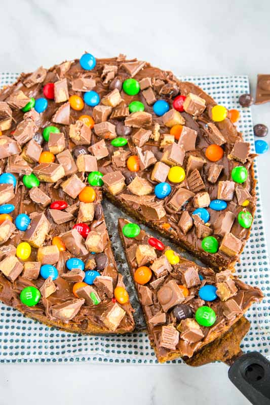 Turn cookies into pizza topped with your favorite candy. Super easy to make and over the top dessert.