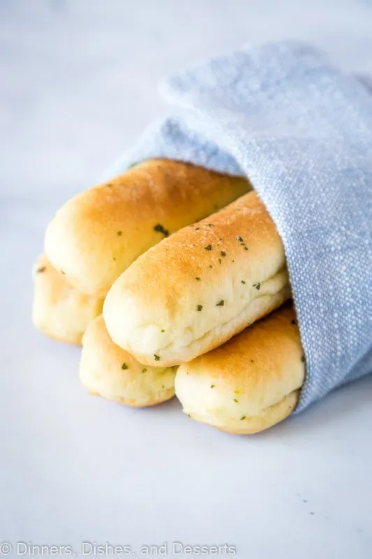 Five breadsticks wrapped in a blue kitchen towel
