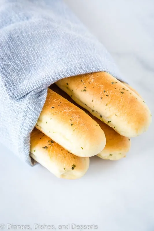 A pile of breadsticks wrapped in a light blue kitchen towel