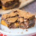 Close up of a salted caramel brownie with a bite missing on a white plate.