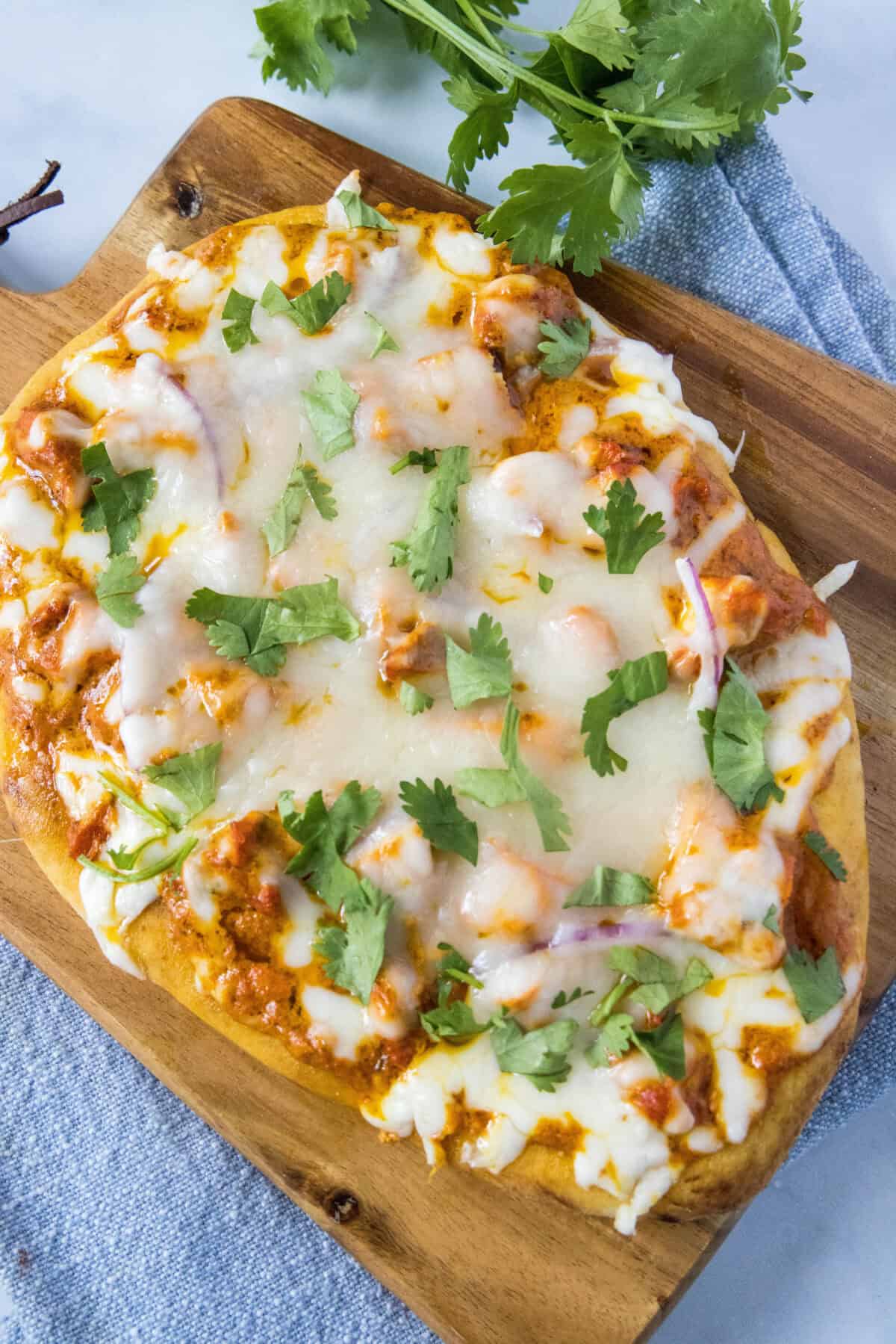 looking down on chicken tikka pizza on cutting board