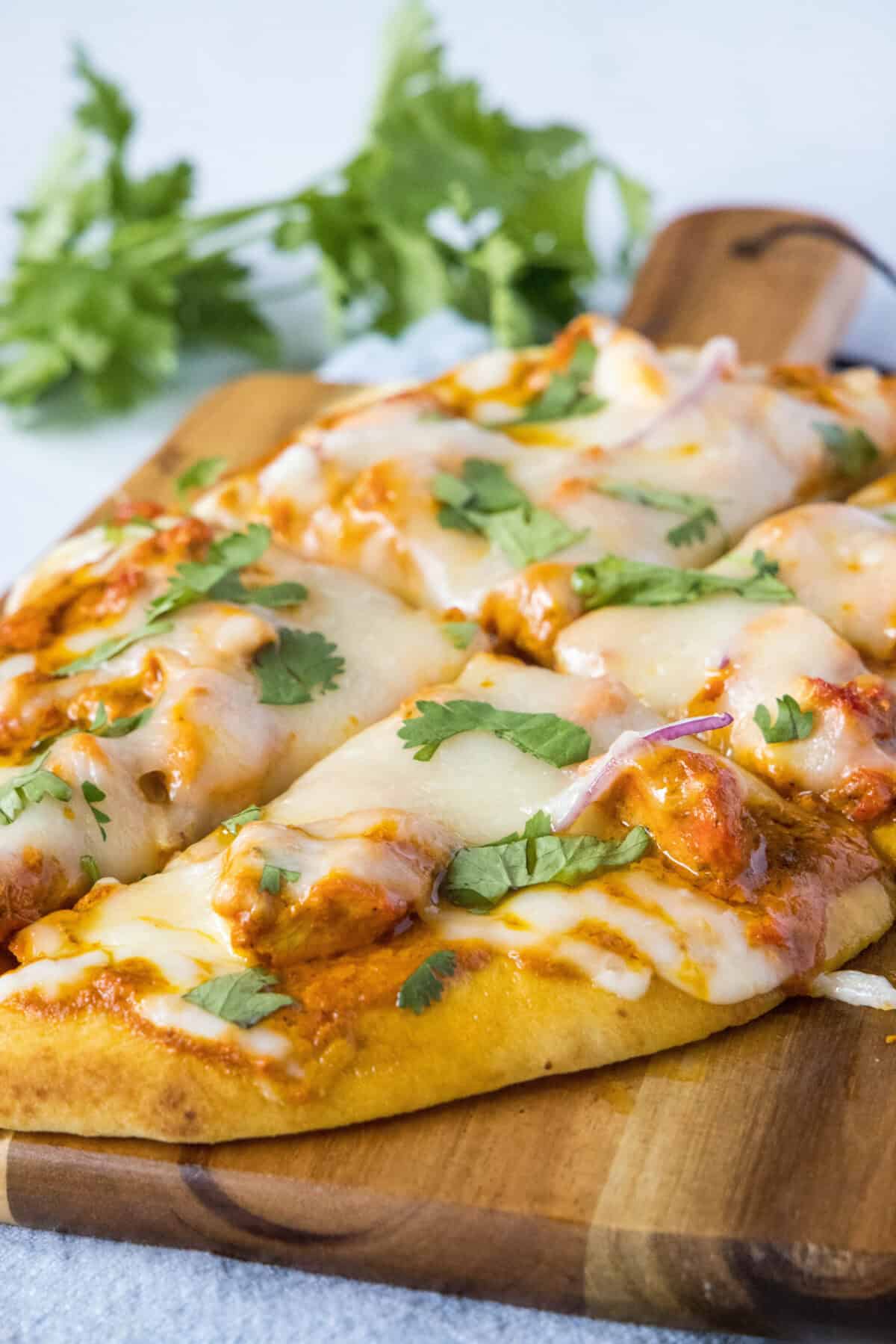 sliced chicken tikka pizza on cutting board